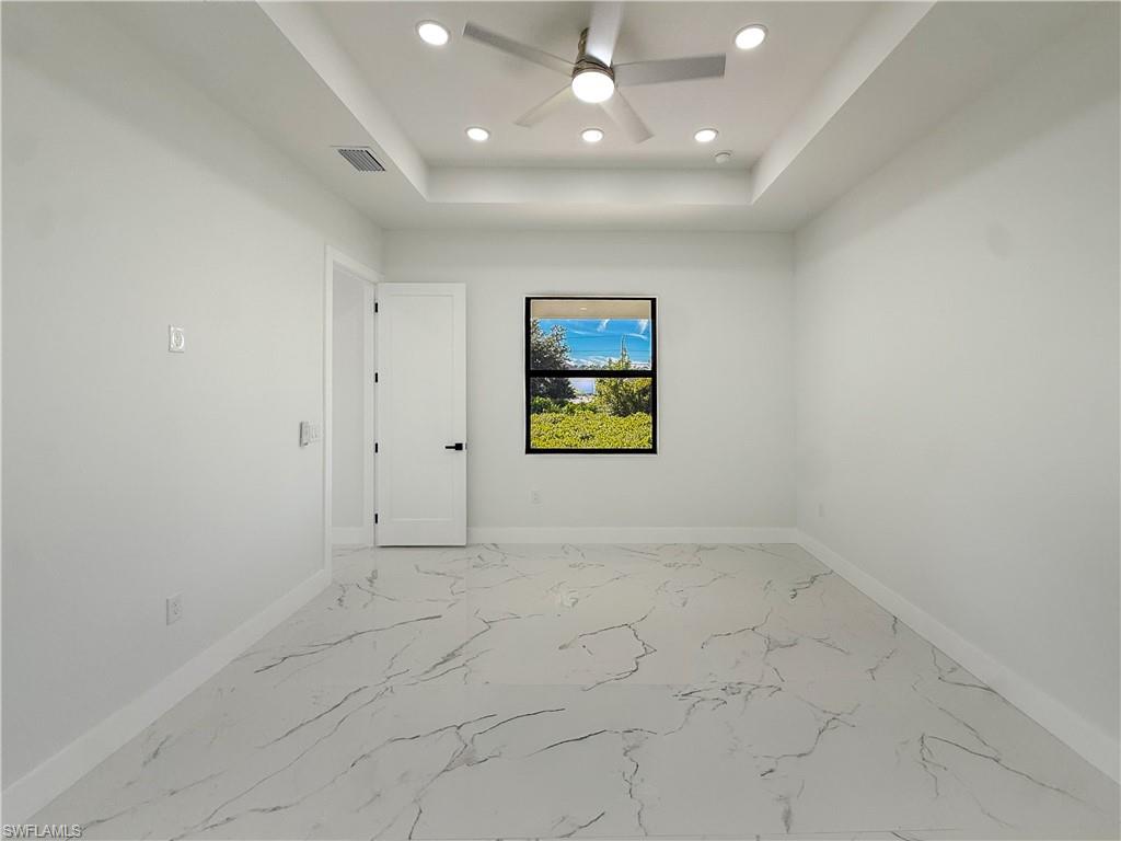 436 Rathburn Street Lehigh Acres, FL 33974 - Photo 13 of 22 Unfurnished room with light marble finish floors, ceiling fan, recessed lighting, and a tray ceiling
