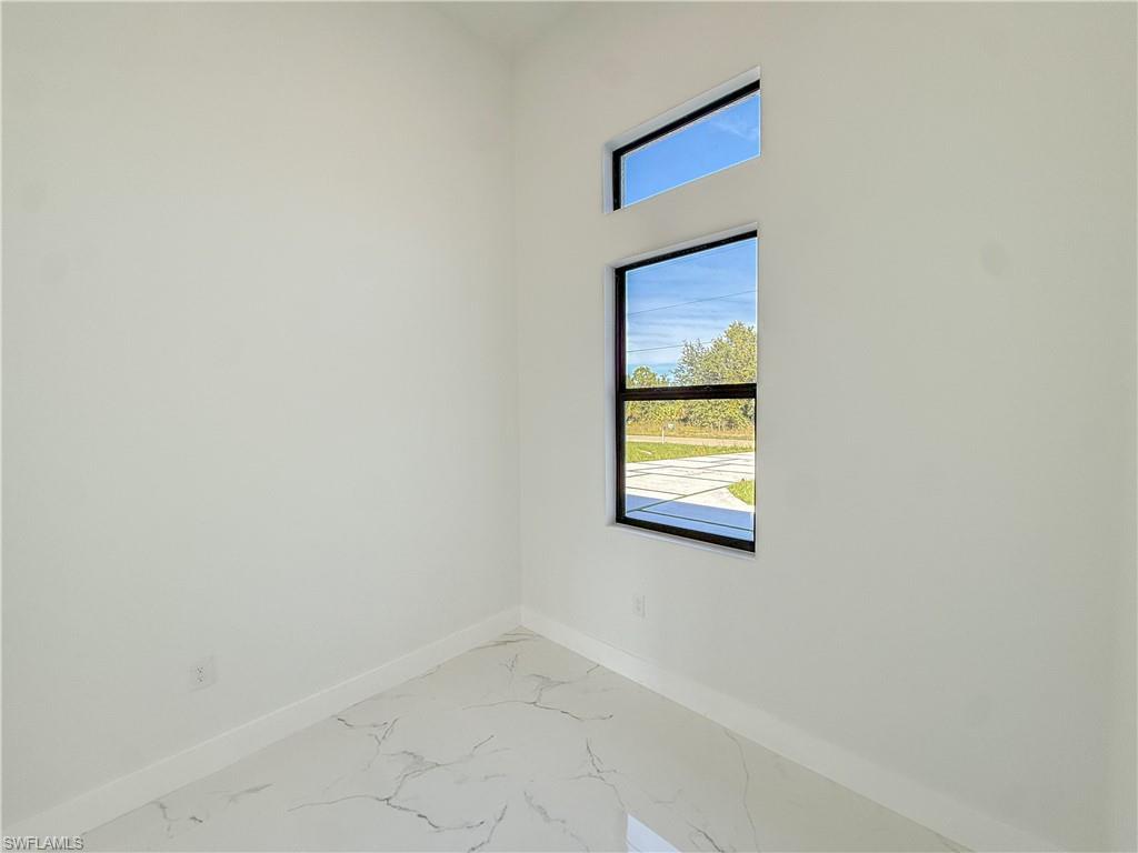 436 Rathburn Street Lehigh Acres, FL 33974 - Photo 15 of 22 Spare room with marble look tiles and baseboards