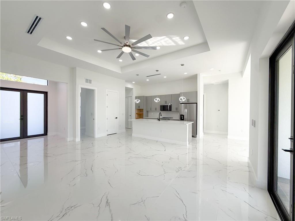 436 Rathburn Street Lehigh Acres, FL 33974 - Photo 2 of 22 Unfurnished living room featuring a raised ceiling, recessed lighting, light marble finish flooring, ceiling fan, and french doors