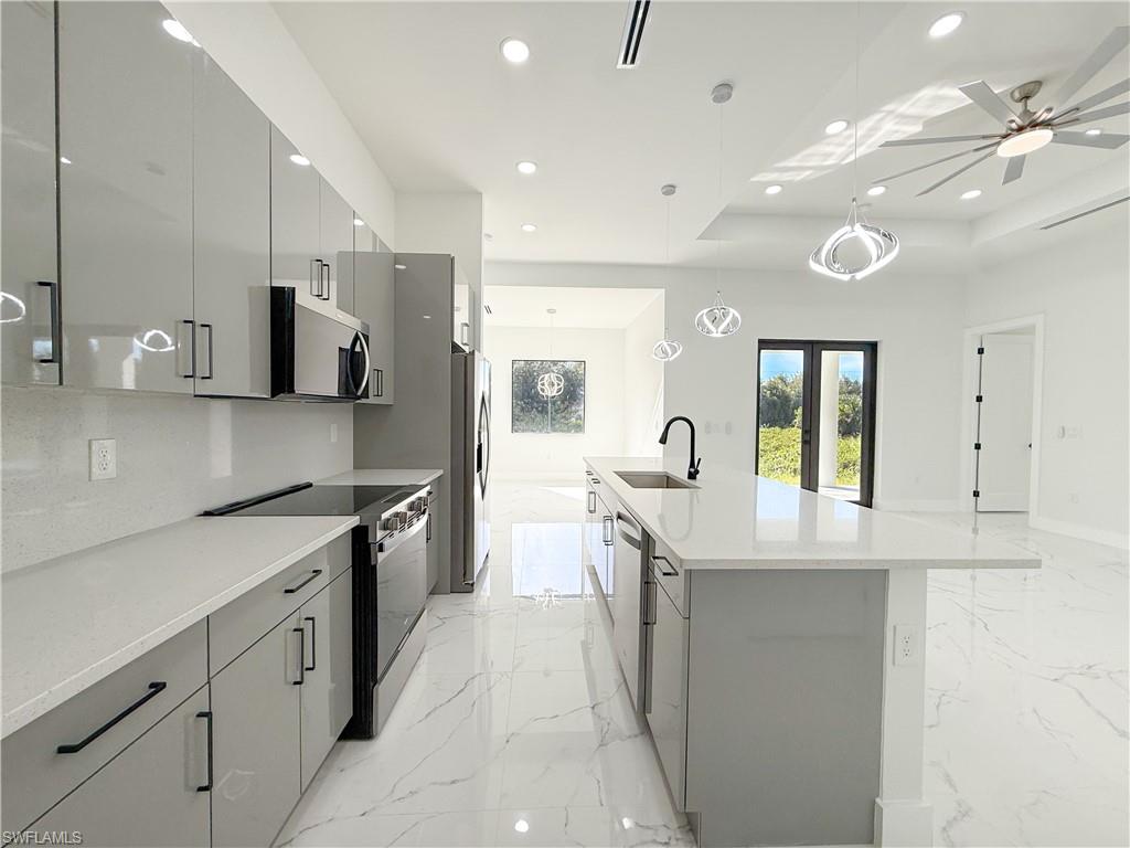 436 Rathburn Street Lehigh Acres, FL 33974 - Photo 3 of 22 Kitchen featuring gray cabinets, hanging light fixtures, stainless steel appliances, light stone counters, and an island with sink