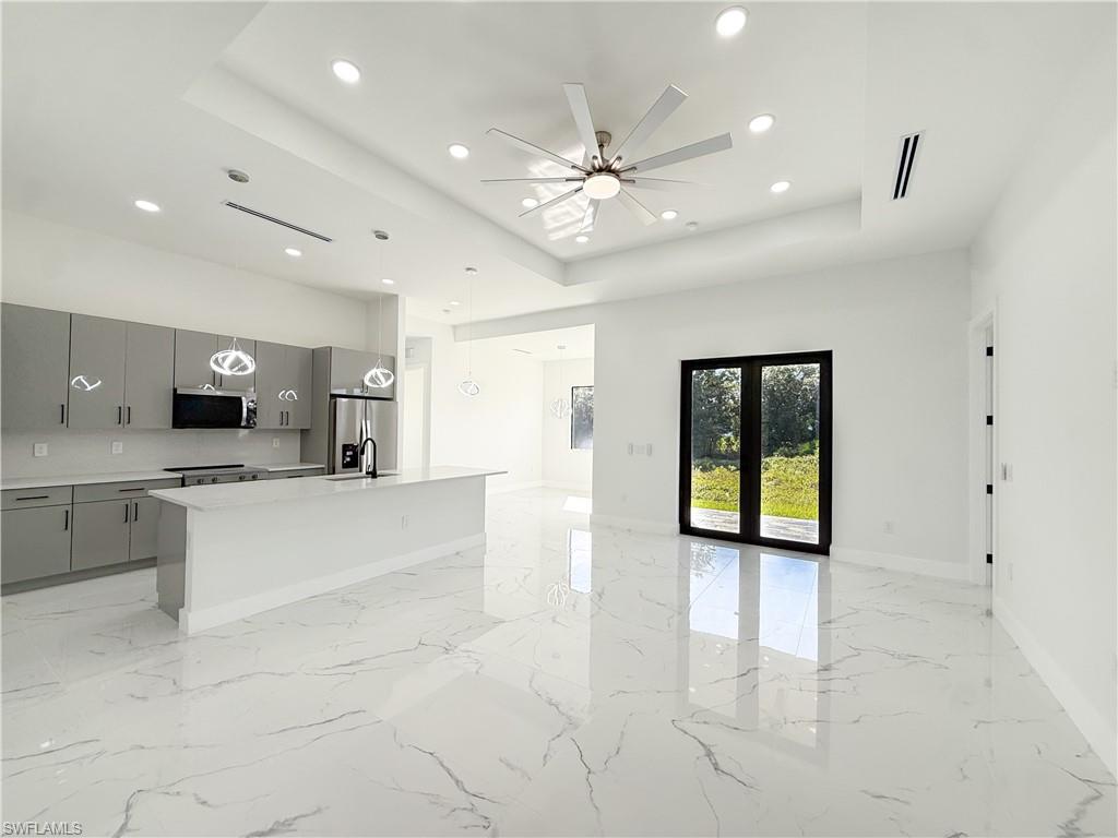 436 Rathburn Street Lehigh Acres, FL 33974 - Photo 22 of 22 Kitchen with a center island with sink, decorative light fixtures, open floor plan, a tray ceiling, and stainless steel appliances