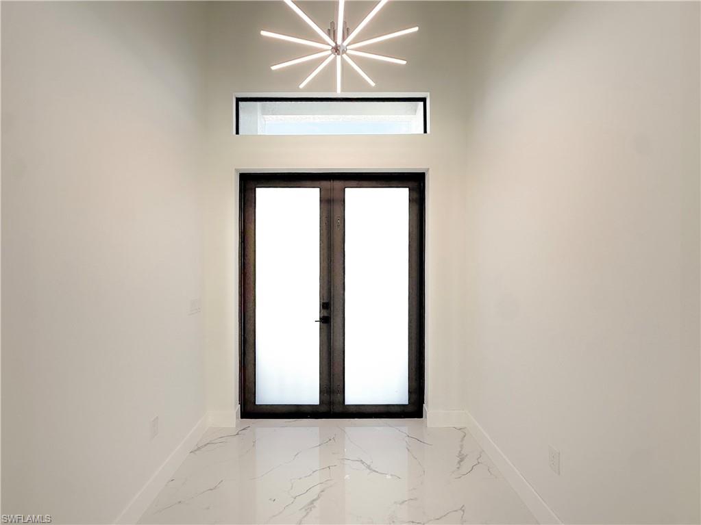 436 Rathburn Street Lehigh Acres, FL 33974 - Photo 8 of 22 Foyer with french doors, light marble finish floors, and a chandelier