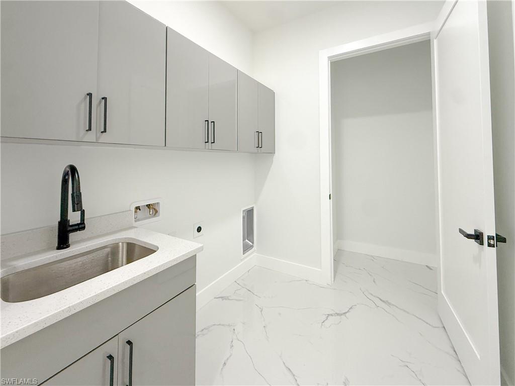 436 Rathburn Street Lehigh Acres, FL 33974 - Photo 9 of 22 Laundry area featuring hookup for a washing machine, light marble finish floors, electric dryer hookup, and cabinet space