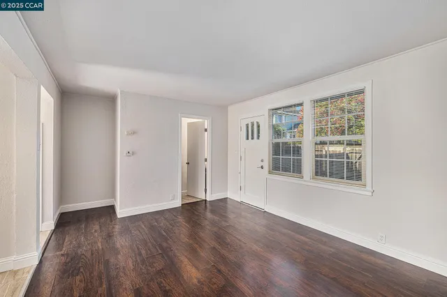 a view of an empty room with wooden floor and windows