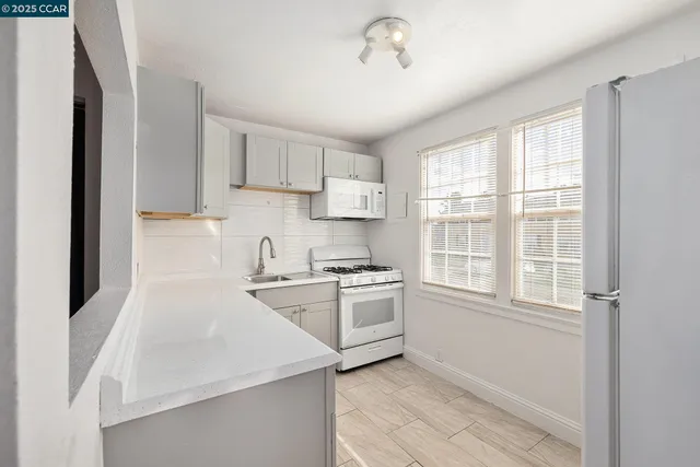 a kitchen with stainless steel appliances granite countertop a stove a sink and white cabinets