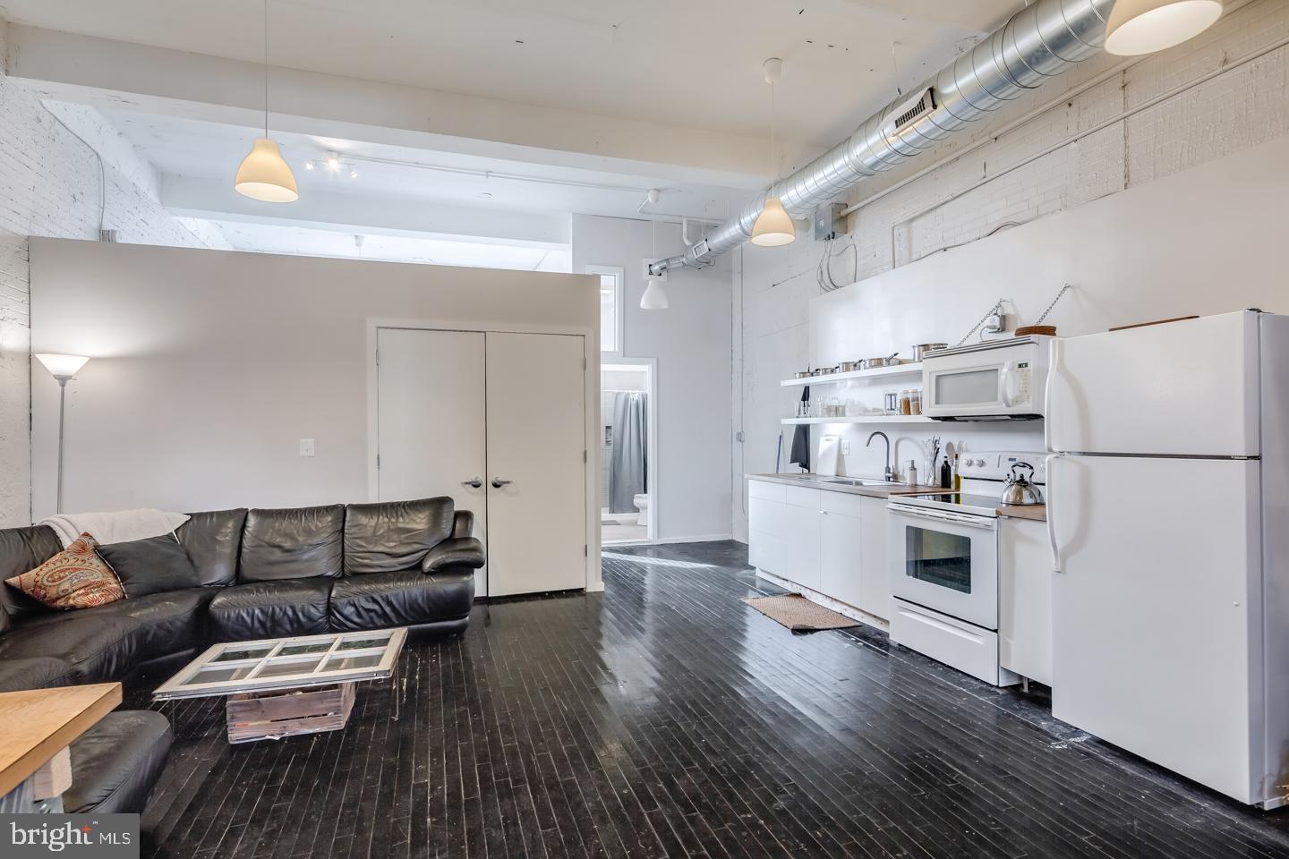 a living room with stainless steel appliances furniture and a wooden floor