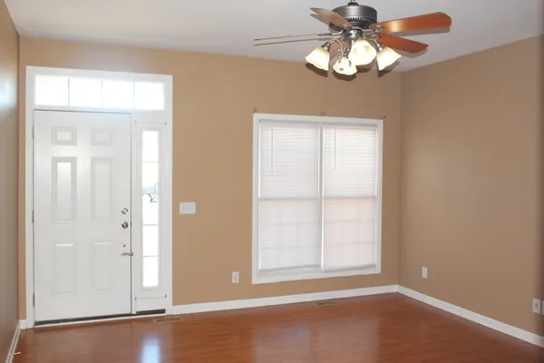 an empty room with wooden floor chandelier and window