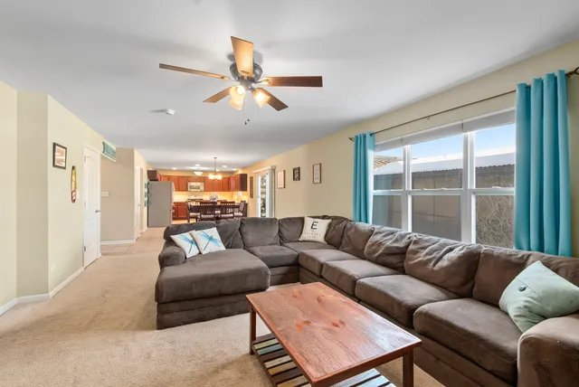 a living room with furniture ceiling fan and a large window