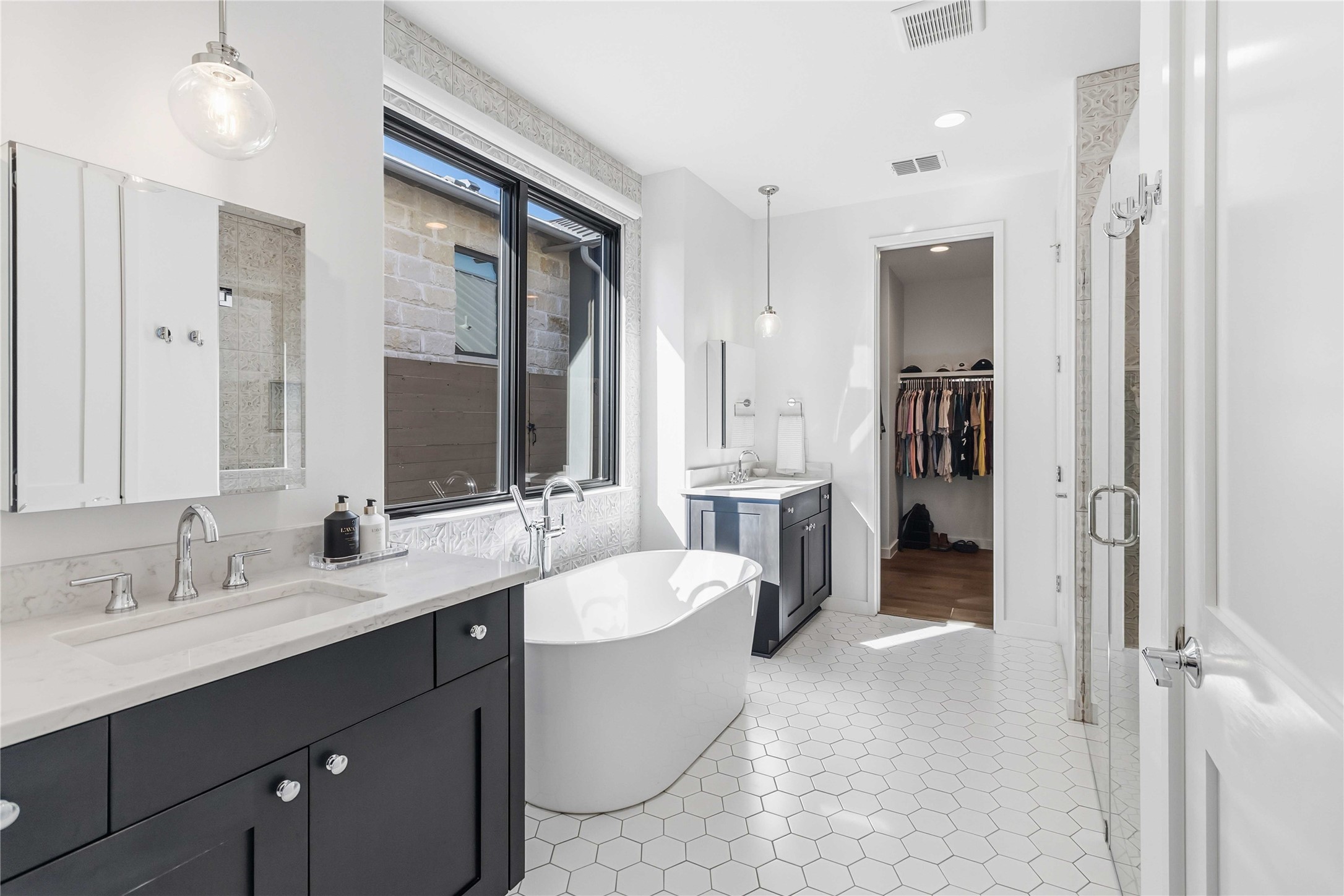 410 Kayak Way Austin, TX 78738 - Photo 17 of 39 Bathroom with two vanities, a walk in closet, a freestanding bath, a shower stall, and recessed lighting