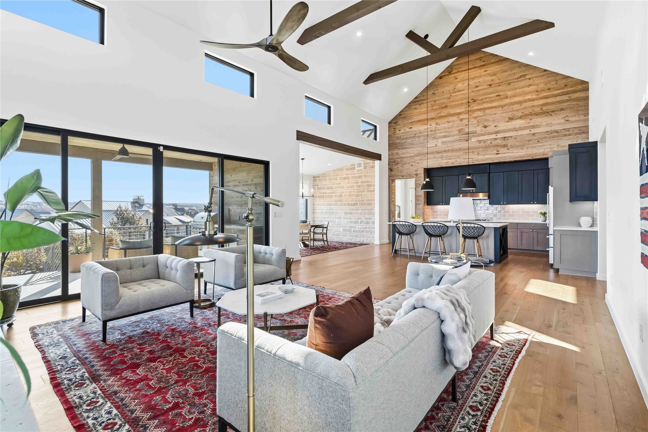 Living room with a high ceiling, light wood finished floors, ceiling fan, and recessed lighting