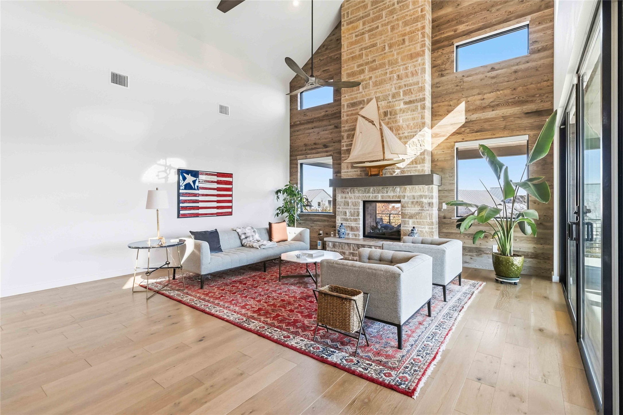 410 Kayak Way Austin, TX 78738 - Photo 7 of 39 Living area featuring lofted ceiling, an outdoor stone fireplace, a ceiling fan, light wood-type flooring, and healthy amount of natural light