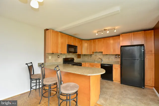 a kitchen with stainless steel appliances granite countertop a refrigerator a stove a sink a dining table and chairs with wooden floor