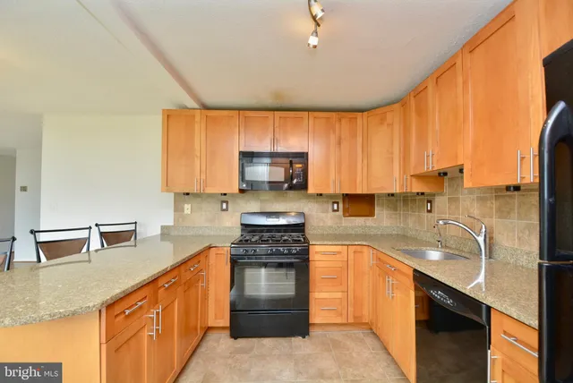 a kitchen with kitchen island granite countertop a sink appliances cabinets and a counter top space