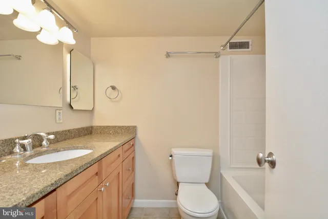 a bathroom with a granite countertop sink toilet and shower