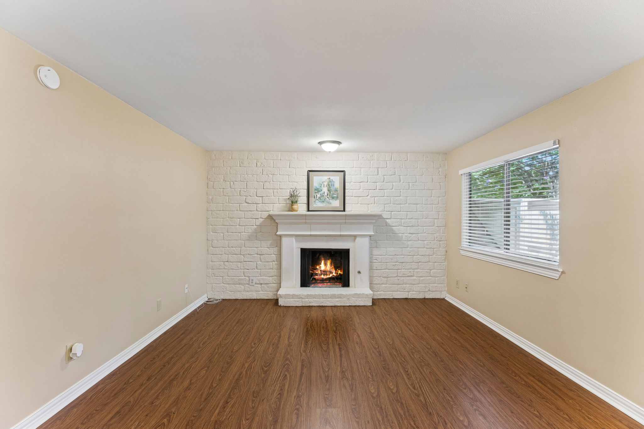 an empty room with wooden floor fireplace and windows