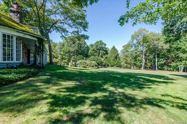 a view of a white house with a big yard and large tree