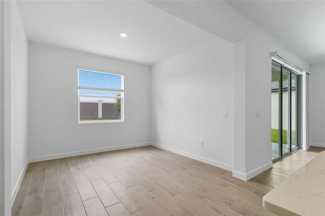 a kitchen with a sink dishwasher a refrigerator and white cabinets with wooden floor