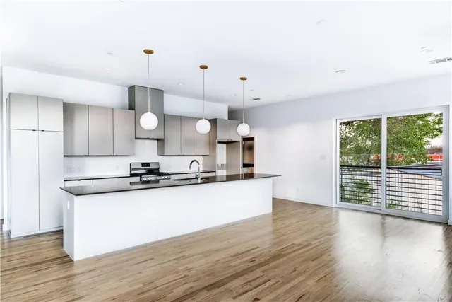 a large kitchen with stainless steel appliances a large counter top a sink a refrigerator and a window