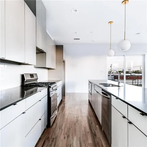 a kitchen with stainless steel appliances granite countertop a sink a stove and a wooden floors