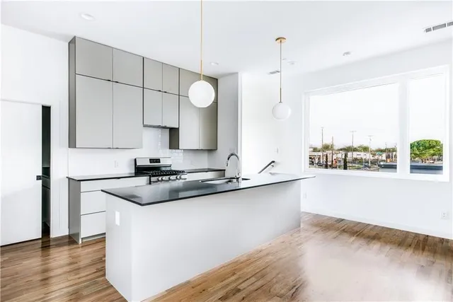a kitchen with stainless steel appliances granite countertop a sink a stove and a wooden floors