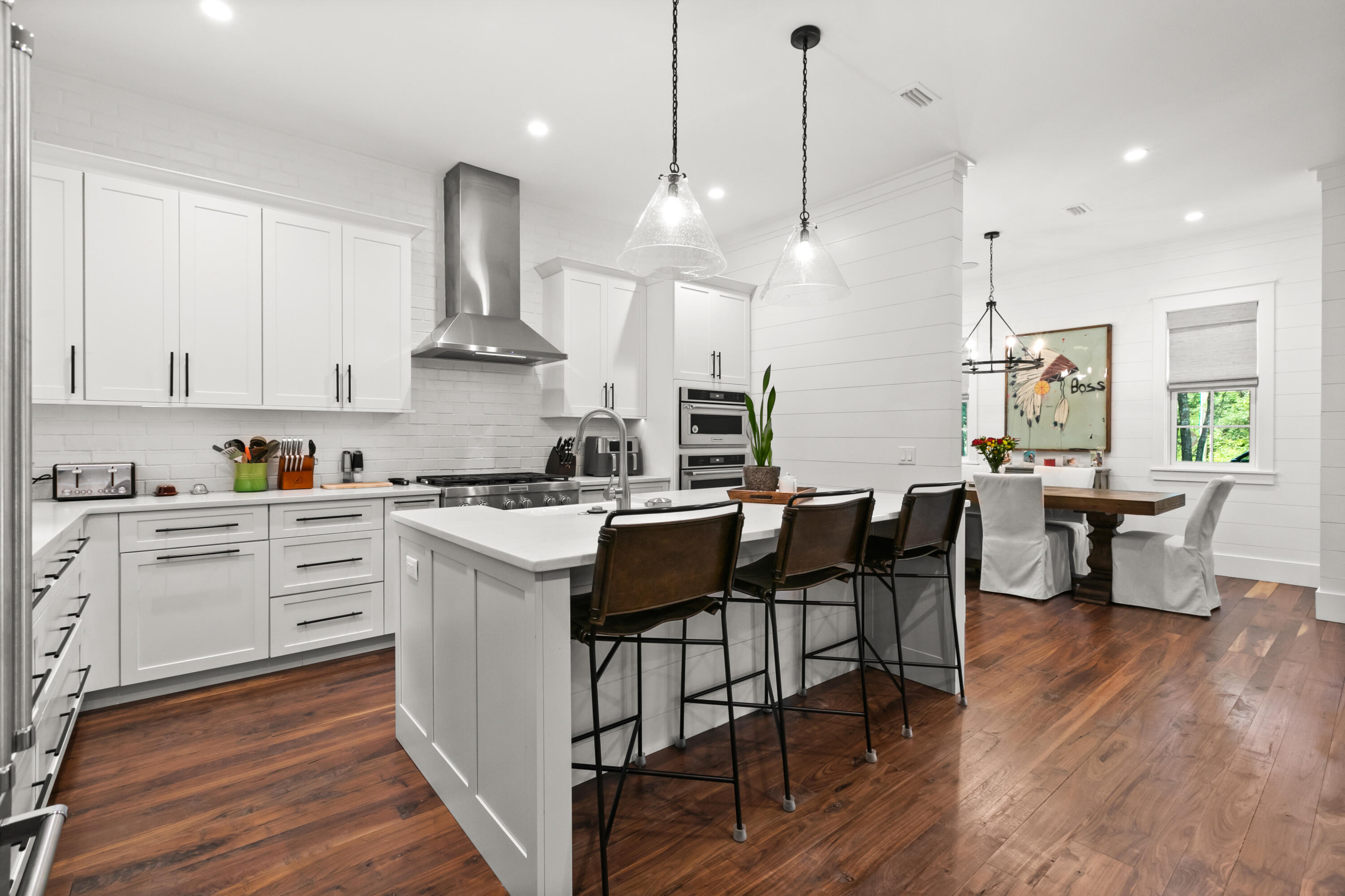 380 Ricker Avenue Santa Rosa Beach, FL 32459 - Photo 8 of 55 a kitchen with stainless steel appliances kitchen island granite countertop a table chairs stove and white cabinets