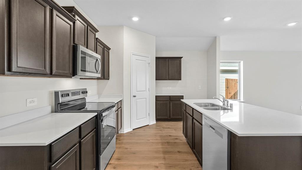 1953 Freeman Street Tyler, TX 75704 - Photo 6 of 32 Modern kitchen featuring dark wood-finish cabinetry, light countertops, and stainless steel appliances