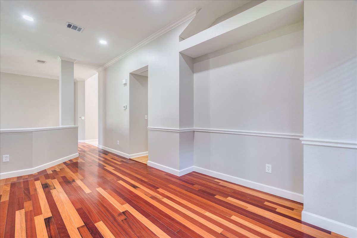 6530 Needham Lane Austin, TX 78739 - Photo 13 of 29 Rich hardwood flooring stretches across an open-concept living space, illuminated by recessed lighting and natural light.