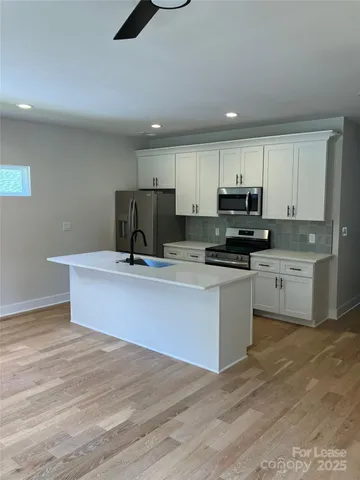 a kitchen with kitchen island a sink stainless steel appliances and cabinets