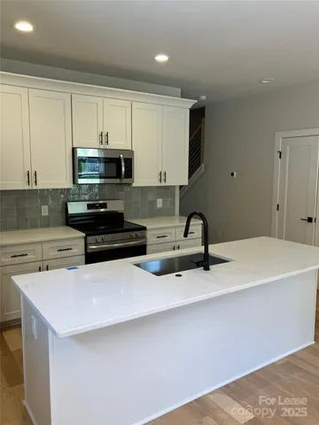 a kitchen with stainless steel appliances a sink a stove a microwave a sink a refrigerator and cabinets