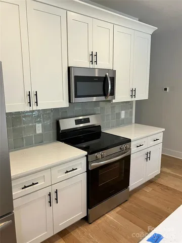 a kitchen with white cabinets and appliances