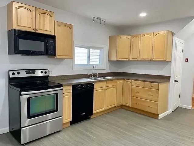 a kitchen with stainless steel appliances granite countertop a stove a sink and a microwave