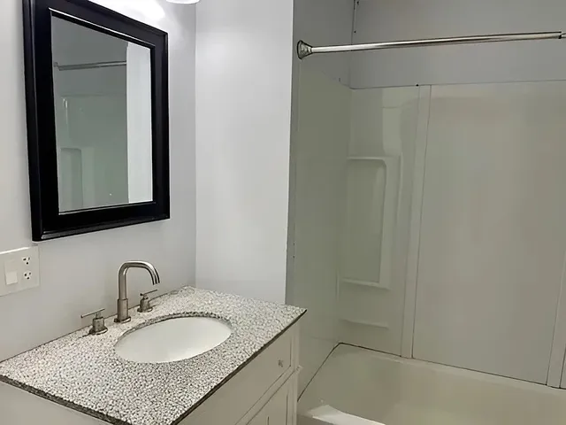 a bathroom with a granite countertop bathtub and shower