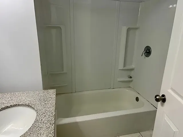 a view of empty room with wooden floor and bathroom