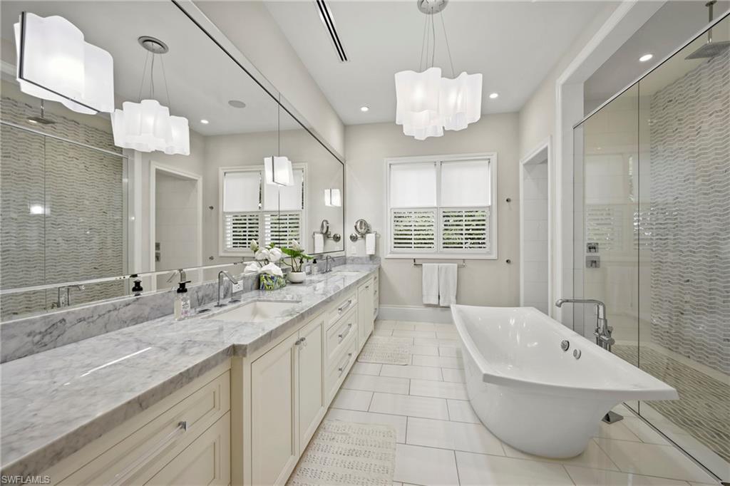 215 3rd Avenue North Naples, FL 34102 - Photo 15 of 47 Full bathroom with a shower stall, double vanity, light tile patterned flooring, a freestanding tub, and suspended lighting