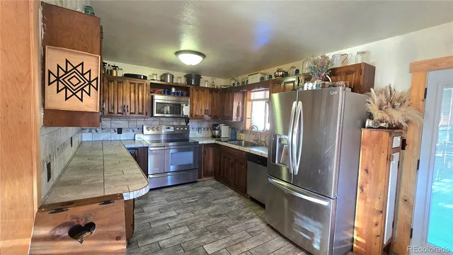 a kitchen with stainless steel appliances granite countertop a refrigerator a stove and a sink with wooden floors