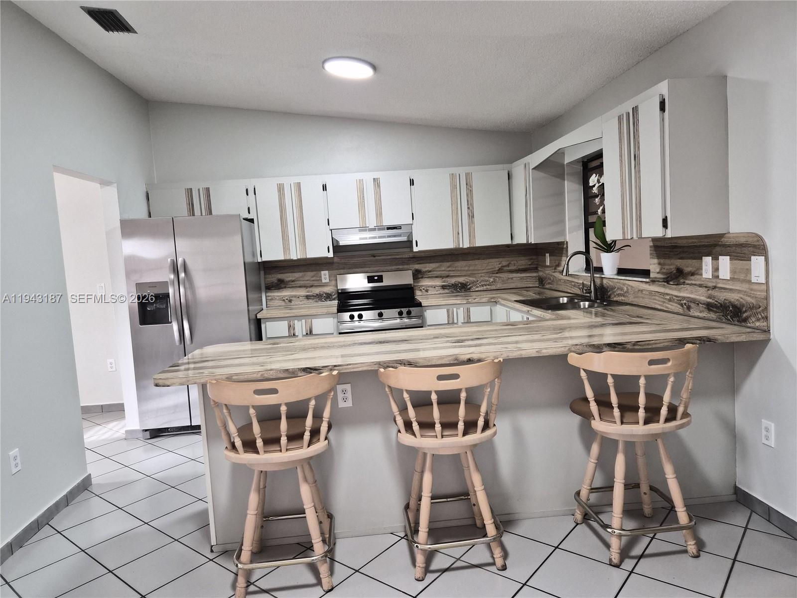 1453 Southwest 137th Place Miami, FL 33184 - Photo 12 of 22 a kitchen with kitchen island granite countertop a sink counter and chairs