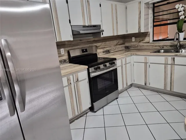 a kitchen with appliances a sink and cabinets