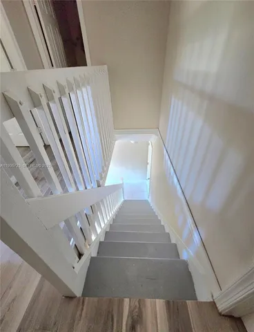 a view of a hallway with wooden floor and staircase