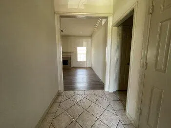 a view of a hallway with wooden floor and a living room