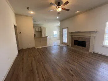 an empty room with wooden floor fireplace and windows