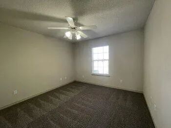 an empty room with a window and a fan