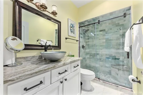 a bathroom with a granite countertop sink toilet a mirror and shower