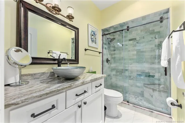 a bathroom with a granite countertop sink toilet a mirror and shower