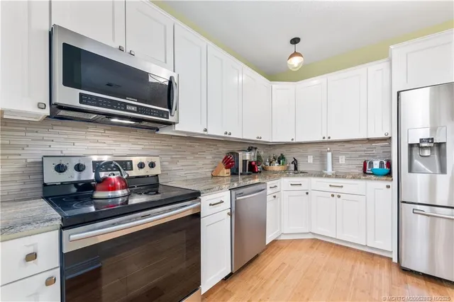 a kitchen with stainless steel appliances granite countertop a stove a sink dishwasher and a refrigerator