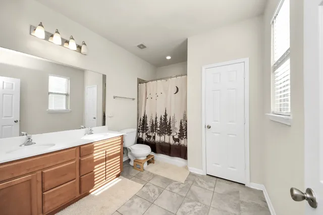 a spacious bathroom with a double vanity sink toilet mirror and bathtub