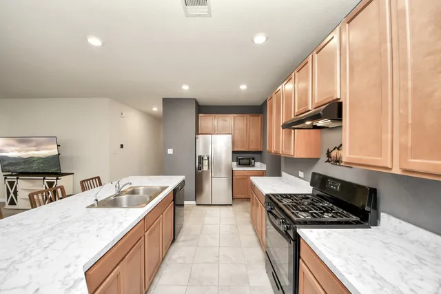 a large kitchen with stainless steel appliances granite countertop a stove a sink dishwasher and a refrigerator with wooden floor