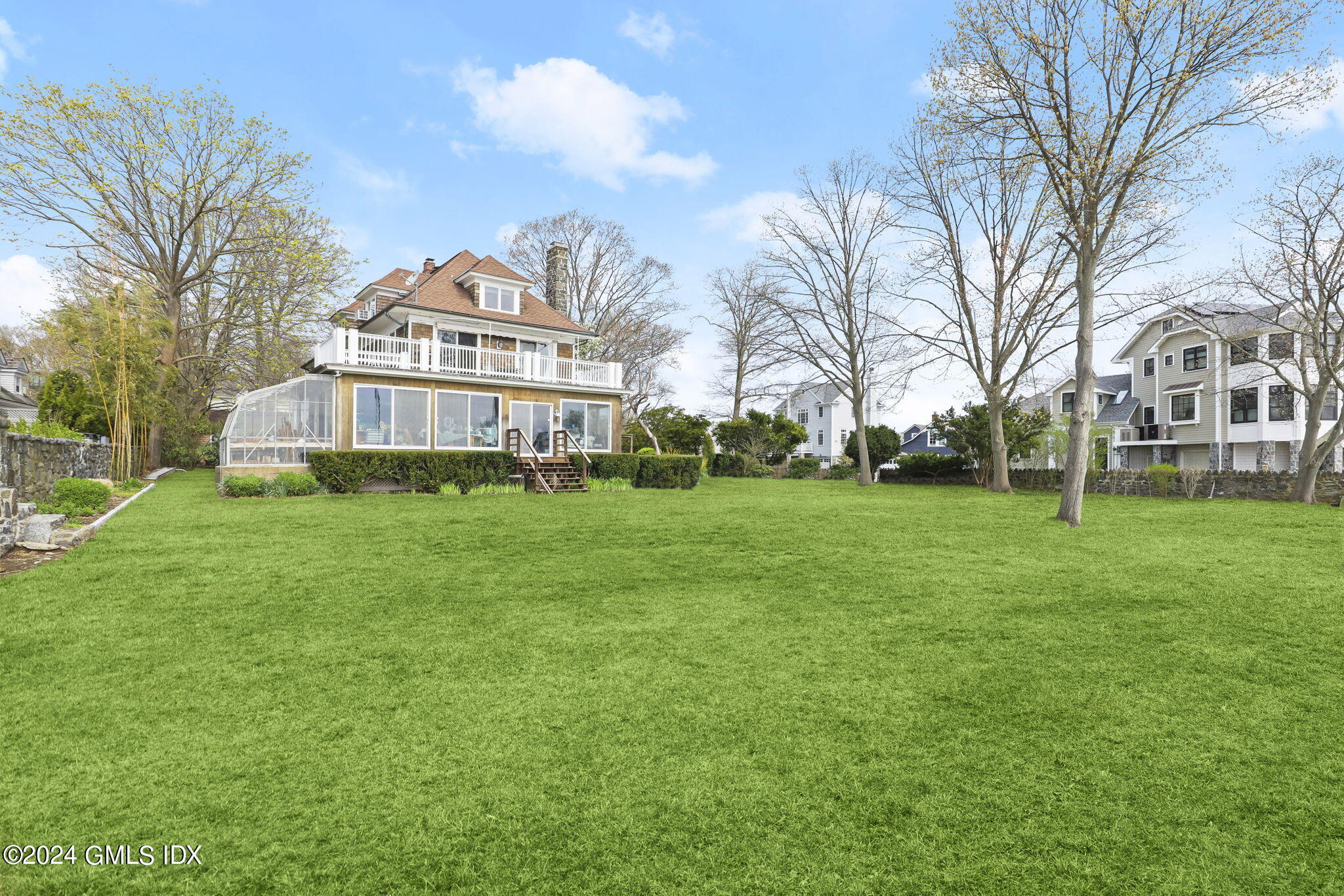 33 Byram Shore Road Greenwich, CT 06830 - Photo 5 of 16 a view of a white house with a big yard and large trees