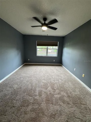 an empty room with windows and chandelier fan