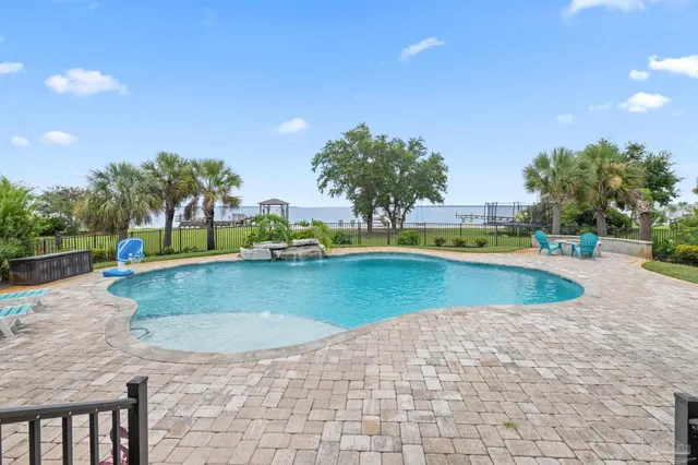 a view of a swimming pool with a patio and a yard