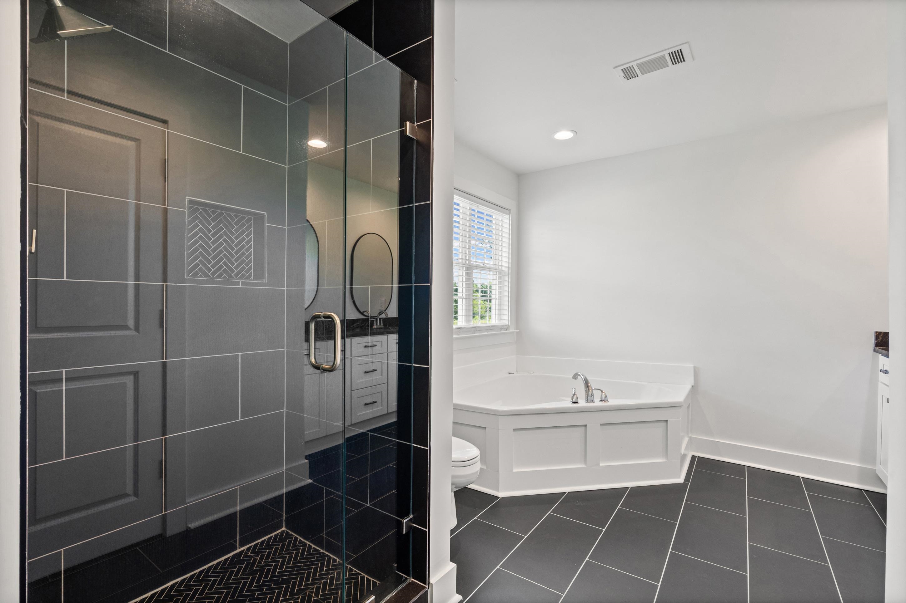 620 Diffee Road Moscow, TN 38057 - Photo 7 of 25 Spacious bathroom featuring a glass-enclosed tile shower, a soaking tub with a window, dark tile flooring